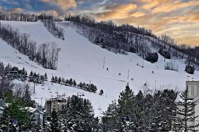 a snow covered ski slope with people skiing on it at Luxury 2 Level Mountain Walk Condo Sauna Jacuzzi Walk to Village in Blue Mountains