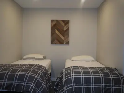two beds in a room with a picture on the wall at Blue Mountain 6BR Chalet Modern Hot Tub Mountain Views Walk to Village in Blue Mountains