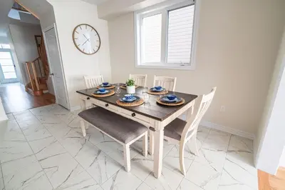 a dining room with a table and chairs and a clock at BRAND NEW home minutes from Niagara Falls. in Thorold