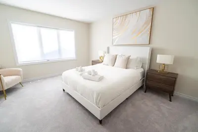 a white bedroom with a white bed and a window at BRAND NEW home minutes from Niagara Falls. in Thorold