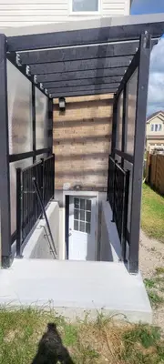 a garage with a white door and a black roof at Comfy basement near KW airport in Kitchener