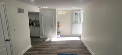 a room with a hallway with a kitchen and a door at Comfy basement near KW airport in Kitchener