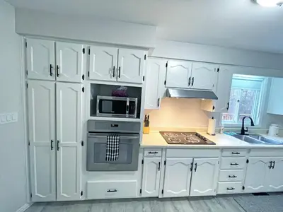 a kitchen with white cabinets and a stove top oven at Forest Retreat - Pool - Games - Fireside Joy in Cayuga