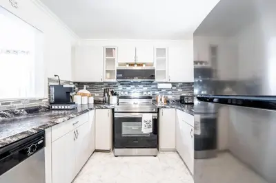 a kitchen with white cabinets and stainless steel appliances at Luxury Stylish Home, Walk to Falls, Fire Pit&More in Niagara Falls