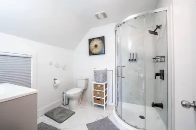 a white bathroom with a shower and a toilet at Luxury Stylish Home, Walk to Falls, Fire Pit&More in Niagara Falls