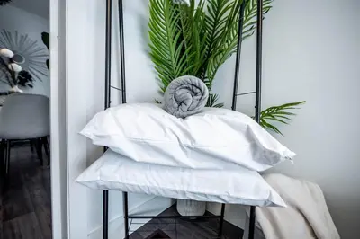 a pile of pillows on a table with a plant at Luxury Stylish Home, Walk to Falls, Fire Pit&More in Niagara Falls