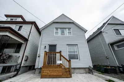 a gray house with a wooden staircase in front of it at Luxury Stylish Home, Walk to Falls, Fire Pit&More in Niagara Falls