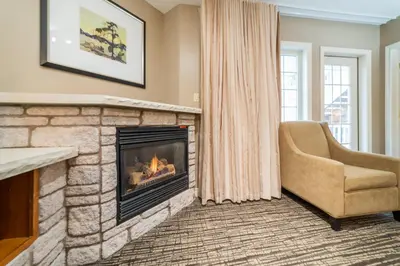 a living room with a fireplace and a chair at Horseshoe Valley Suites - The Aurora in Shanty Bay