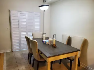 a dining room table and chairs with a black table and white walls at RAESABU GUEST HOUSE in Brampton