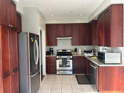 a kitchen with wooden cabinets and a stainless steel refrigerator at Spacious 5BR Home for Families & Business Travelers in Ajax