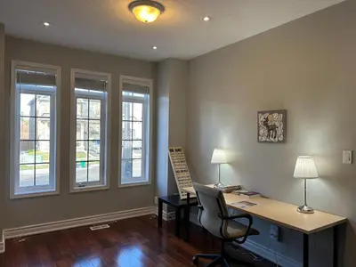 an office with a desk and a chair and windows at Spacious 5BR Home for Families & Business Travelers in Ajax