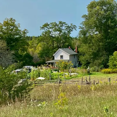 a white house in the middle of a field at Fells Meadows Farmhouse on Country Property in Castleton