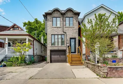 a brick house with a yellow staircase in front of it at Beautiful 3BR House in the Heart of Greek Town in Toronto