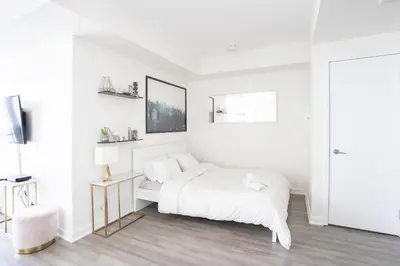 a white bedroom with a bed and a tv at Beautiful Luxurious Modern Condo With Breathtaking Views in Toronto