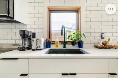 a white kitchen with a sink and a window at Tiny House Haven in Peterborough