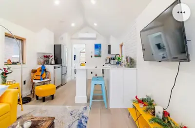 a kitchen and living room with a blue stool at Tiny House Haven in Peterborough