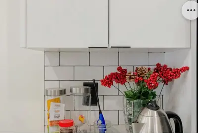 a vase of red flowers on a kitchen counter at Tiny House Haven in Peterborough