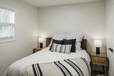 a bedroom with a large white bed with two lamps at The Little White Haus in Niagara on the Lake