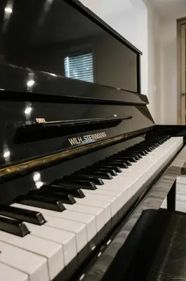 a black piano sitting in a room at The Little White Haus in Niagara on the Lake