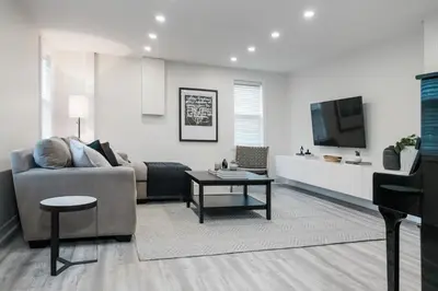 a living room with a couch and a tv at The Little White Haus in Niagara on the Lake