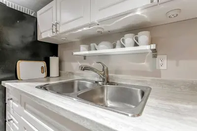 a kitchen with a stainless steel sink and white cabinets at Lakeside Retreat near Toronto in Mississauga