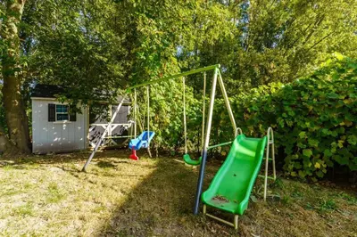 a playground in a yard with a swing at Fun & Cozy Retreat: Nature & Games in Trenton