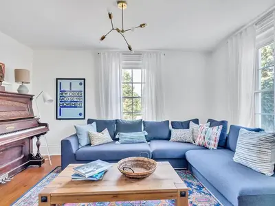 a living room with a blue couch and a piano at The Gem - Beautiful farmhouse with hot tub in West Lake