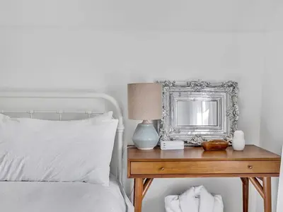 a bedroom with a bed with a table with a mirror at The Gem - Beautiful farmhouse with hot tub in West Lake