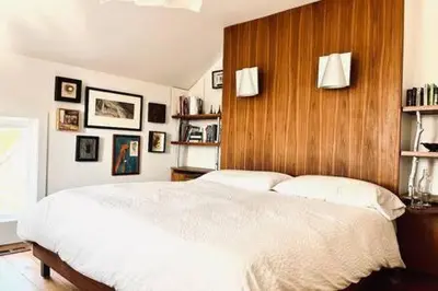 a bedroom with a white bed with a wooden wall at Away in the County-Sandbanks Pec in Cherry Valley