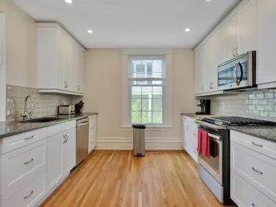 a kitchen with white cabinets and a wooden floor at Wind & Waves - Wellington waterfront with Satellite TV & fire pit in Wellington