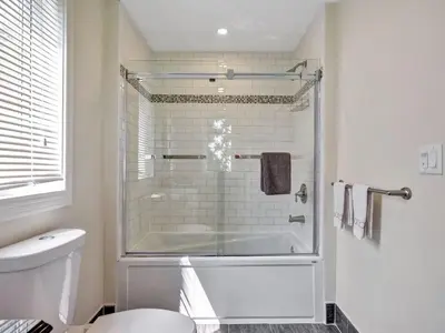 a white bathroom with a shower and a toilet at Wind & Waves - Wellington waterfront with Satellite TV & fire pit in Wellington