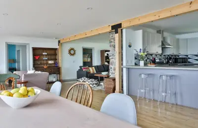 a kitchen and living room with a table with a bowl of fruit at Lakeside PEC: Beautiful Waterfront & Patio in Wellington