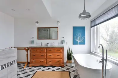 a bathroom with a tub and a sink and a mirror at Lakeside PEC: Beautiful Waterfront & Patio in Wellington