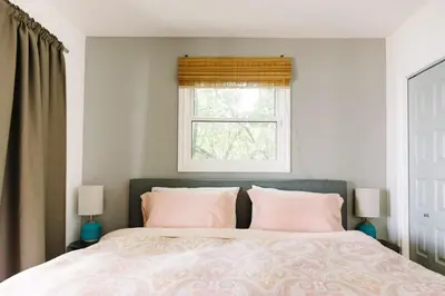 a bedroom with a bed with pink pillows and a window at Lakeside PEC: Beautiful Waterfront & Patio in Wellington
