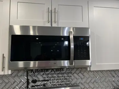 a stainless steel microwave in a kitchen with white cabinets at Tosam Luxury Lodge Two Bedroom Suite in Brampton