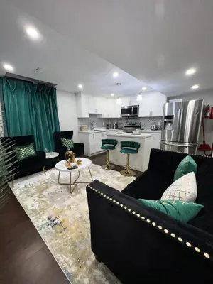 a living room with a black couch and a kitchen at Tosam Luxury Lodge Two Bedroom Suite in Brampton