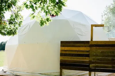 a large white tent sitting next to a wooden box at Open Sky Glamping Kawartha Dome in Marmora