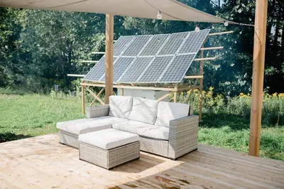 a wicker chair and stool on a wooden deck with a solar at Open Sky Glamping Kawartha Dome in Marmora