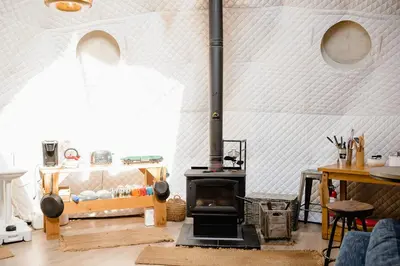 a living room with a wood stove in a room at Open Sky Glamping Kawartha Dome in Marmora