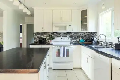 a kitchen with white appliances and a black counter top at Grays Lane - Minutes to Sandbanks in Bloomfield
