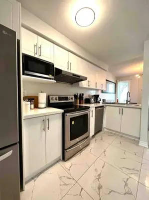 a large kitchen with white cabinets and appliances at Charming Home in Prime Location North of Toronto in Richmond Hill