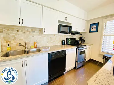 a kitchen with white cabinets and a sink and a stove at Blue Mountain Suites in Blue Mountains