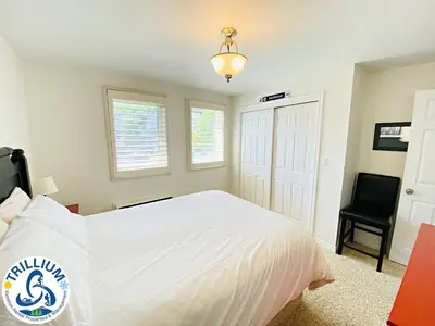 a bedroom with a white bed and a black chair at Blue Mountain Suites in Blue Mountains