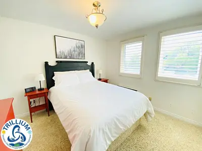 a bedroom with a white bed and two windows at Blue Mountain Suites in Blue Mountains