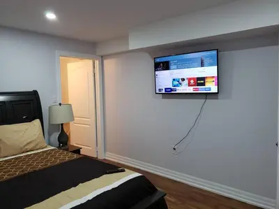 a bedroom with a bed and a flat screen tv on the wall at Luxurious 1BR - 1BA Apt Modern Bright with free parking-pc in Brampton