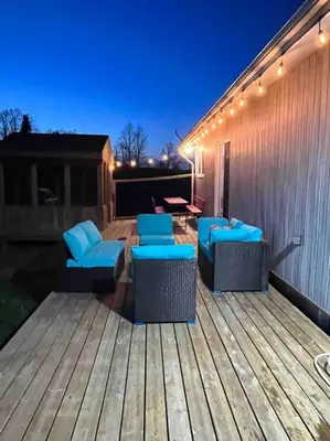 a deck with blue chairs and a table with lights at Farm House in Coldwater