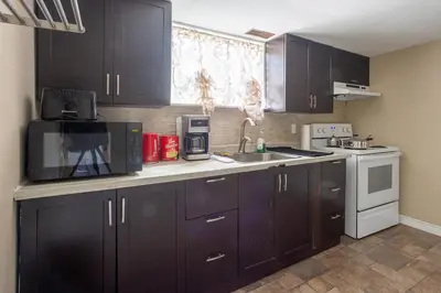 a kitchen with black cabinets and a sink and a microwave at Private room with TVnetflix and free parking in Pickering