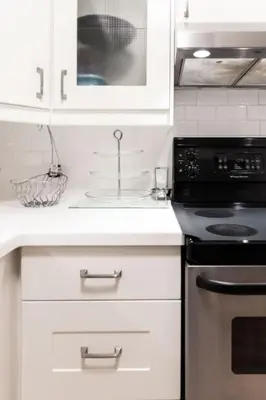 a kitchen with white cabinets and a sink and a stove at Prime Location 2BR with KingBed in Vibrant Toronto in Toronto