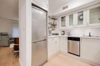a kitchen with white cabinets and a stainless steel refrigerator at Prime Location 2BR with KingBed in Vibrant Toronto in Toronto