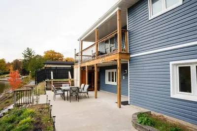 a patio with a table and chairs next to a house at Riverfront Cottage Sauna Canoe Included Kids Playroom Nature Escape in Wasaga Beach